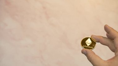Gül turuncusu arka planda sergilenen ETHEREUM altın sikke eli bir sürü yaratıcı kopya alanı.