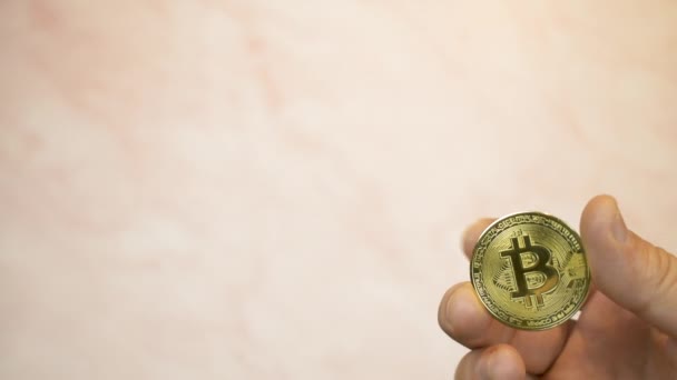 Правая Рука Показывает Золотую Bitcoin Бледно Оранжевом Фоне — стоковое видео