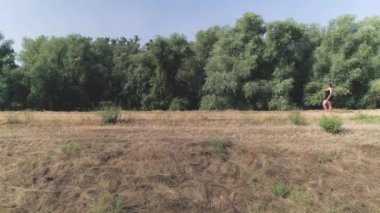 Mavi şapkalı bir kadın yüksek bir yolda yürüyor. Profil. Sıcak bir günün tadını tek başına çıkaran bir kadın. Rahatlamak için sıradan bir yürüyüş. Yükseltilmiş patika.