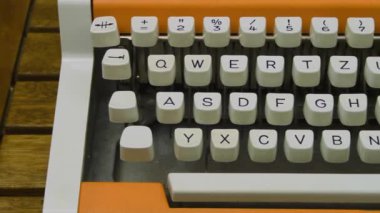 Typewriter keyboard close up. Camera travel dolly left to right. Nice stylish orange vintage mechanical typing machine.