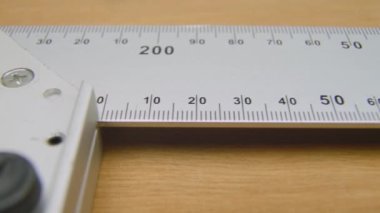 Square angle ruler. Construction Carpenter ruler on a wooden surface L shape straightedge.Square angle ruler lying on a table, ready to be used in construction, woodworking. Close up, macro. Wooden surface, background.