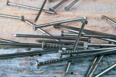 Steel nails spread over a reclaimed wood table.Steel woodworking nails lying ona a table made of old vintage reclaimed wood.