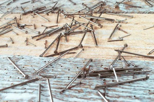 Steel nails spread over a reclaimed wood table.Steel woodworking nails lying ona a table made of old vintage reclaimed wood. Top view. 