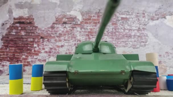 後ろの損傷したレンガの壁 ウクライナとロシアの旗の色でキューブの間におもちゃのタンクT 55とジオラマ ウクライナ紛争での戦争のイラストは 特別な操作を攻撃します ドリーショットを暴いて — ストック動画