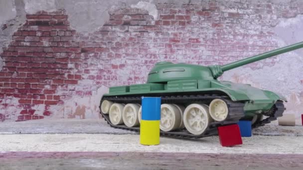 ウクライナとロシアの旗の色でキューブの間におもちゃのタンクT 55とジオラマ ウクライナ紛争での戦争のイラストは 特別な操作を攻撃します ドリーショットを暴いて 素敵なコピースペース — ストック動画