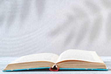 Gri arkaplanlı, doğal gölgeli bir kitap.