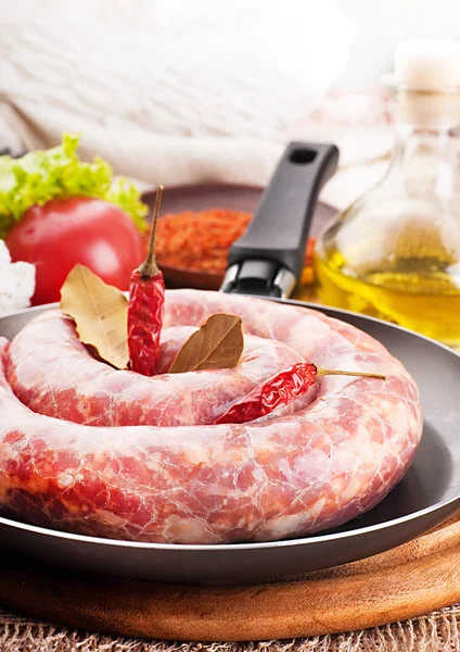 Home sausage in a frying pan, pepper and laurel sheet — Stock Photo, Image