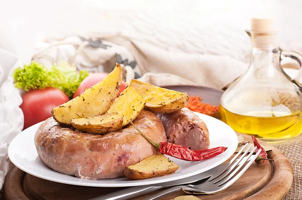 Home sausage with the baked potato, pepper and laurel sheet — Stock Photo, Image