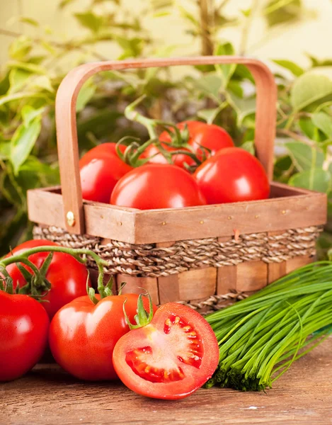 Tomates y cebollas verdes en una cesta triturada — Foto de Stock