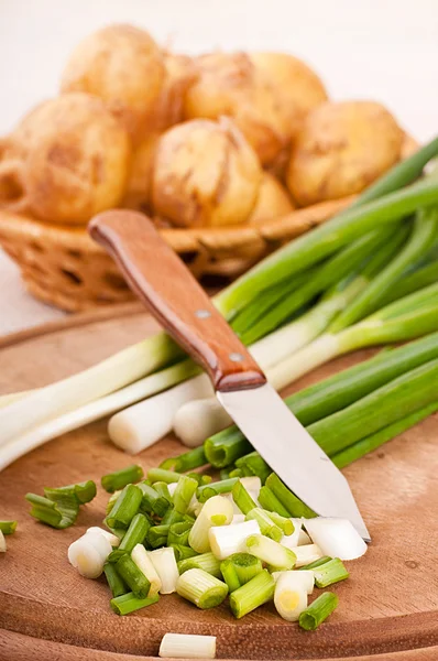 Grüne Zwiebeln auf einem Holzbrett geschnitten — Stockfoto