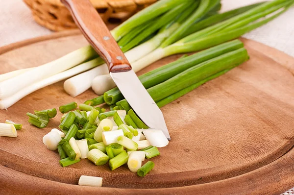 Grüne Zwiebeln auf einem Holzbrett geschnitten — Stockfoto