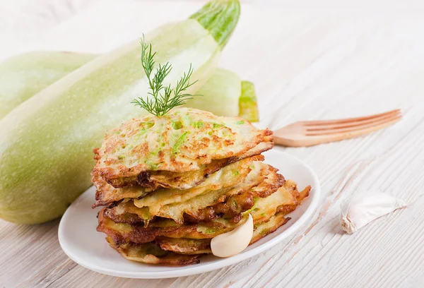 Green zucchini pancakes on a wooden old board