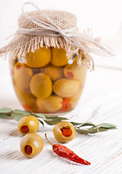 Banca di olive con pepe su un'asse di legno — Foto Stock