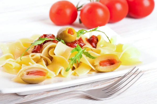 Pasta with tomato and arugula on the wooden table — Stock Photo, Image