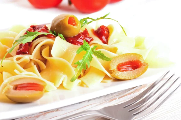 Pasta with tomato and arugula on the wooden table — Stock Photo, Image