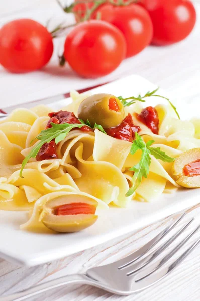 Pasta with tomato and arugula on the wooden table — Stock Photo, Image