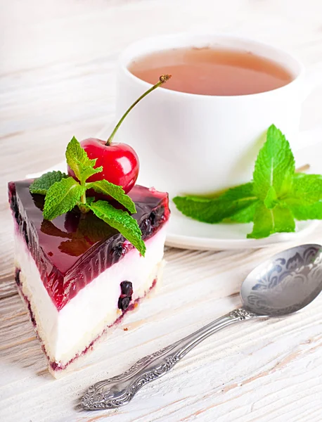 Cherry cheesecake med te på ett träbord — Stockfoto