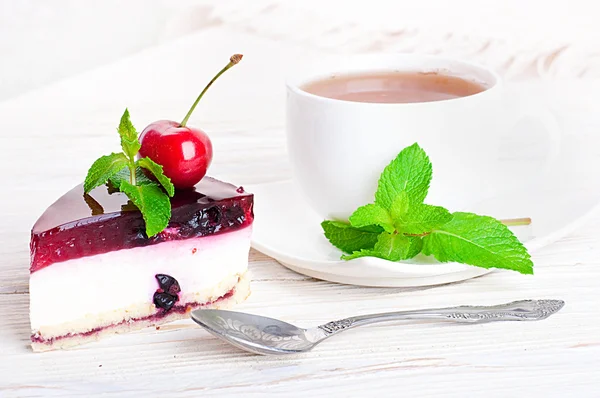 Cherry cheesecake med te på ett träbord — Stockfoto