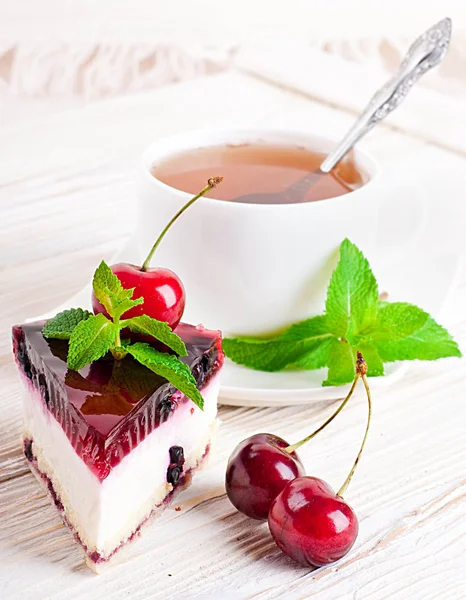 Cherry cheesecake med te på ett träbord — Stockfoto
