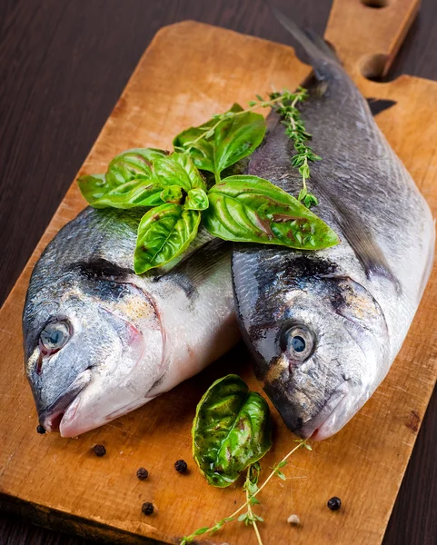 Pesce dorado con limone e spezie su una tavola di legno — Foto Stock