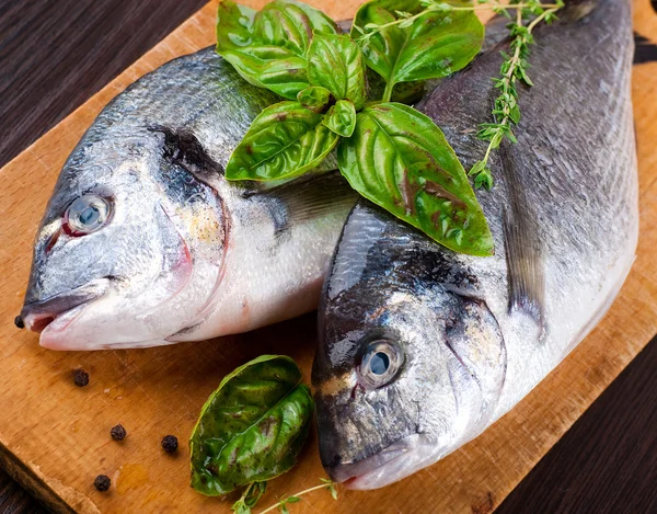 Peixe dorado com limão e especiarias em uma tábua de madeira — Fotografia de Stock