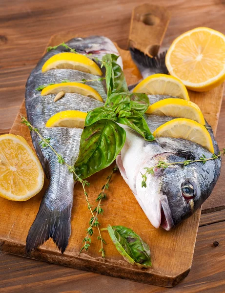 Peixe dorado com limão e especiarias em uma tábua de madeira — Fotografia de Stock