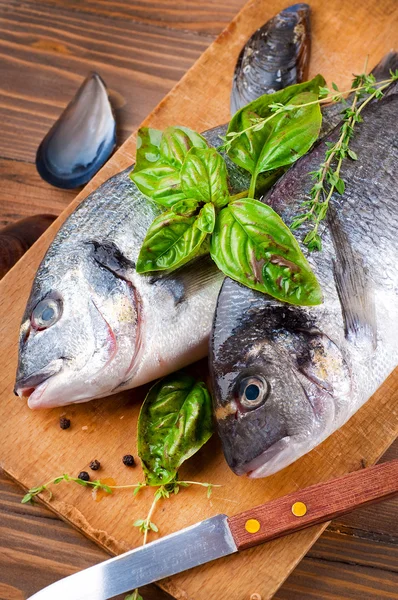 Peixe dorado com limão e especiarias em uma tábua de madeira — Fotografia de Stock