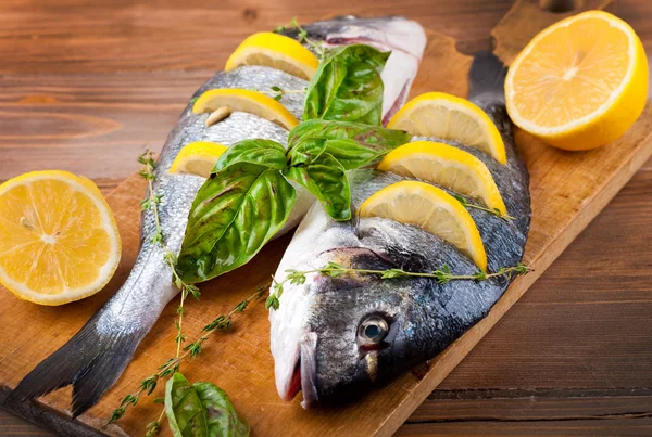 Ryby dorado z cytryny i przyprawy na desce — Zdjęcie stockowe