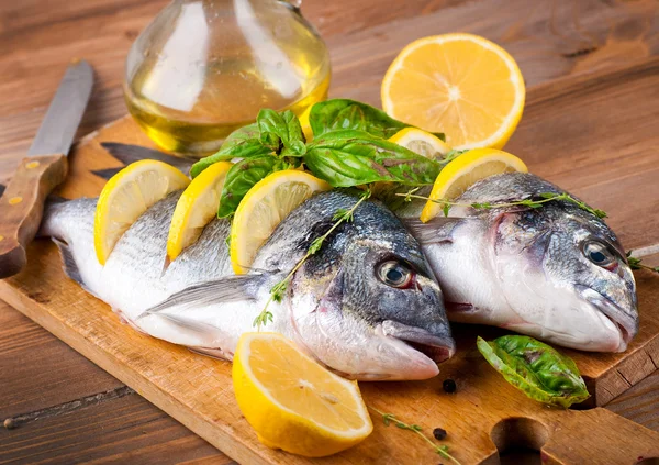 Pesce dorado con limone e spezie su una tavola di legno — Foto Stock