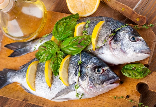 Dorado pescado con limón y especias en una tabla de madera — Foto de Stock