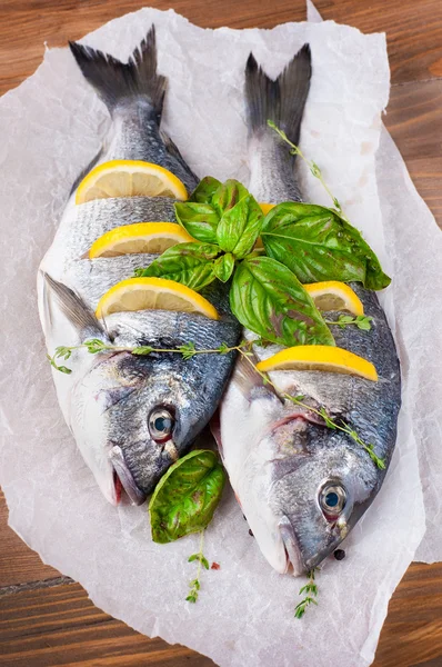 Pesce dorado con limone e spezie su una tavola di legno — Foto Stock