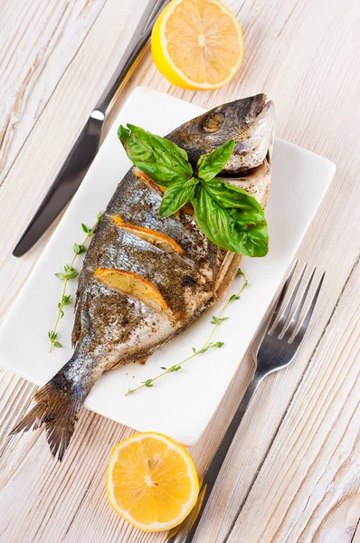 Dorado vis met citroen en specerijen op een houten bord — Stockfoto