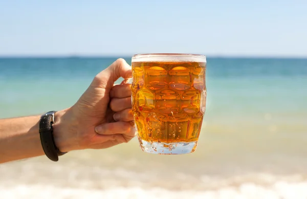 Mok van bier in de hand — Stockfoto