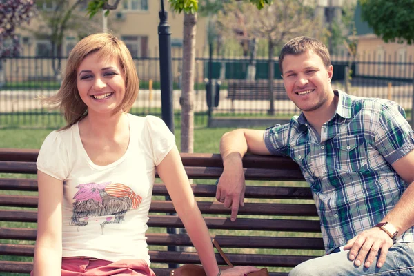 Νεαρό ζευγάρι κάθεται στον πάγκο στο πάρκο — Φωτογραφία Αρχείου