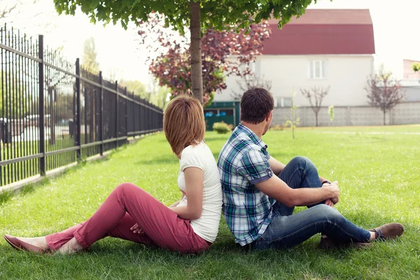 Young couple sitting outdoors on bench bored in relationship — Stock Photo, Image