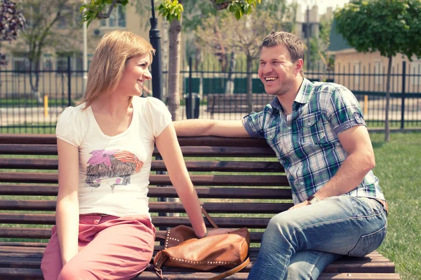 Young couple sitting on bench in park — Stock Photo, Image