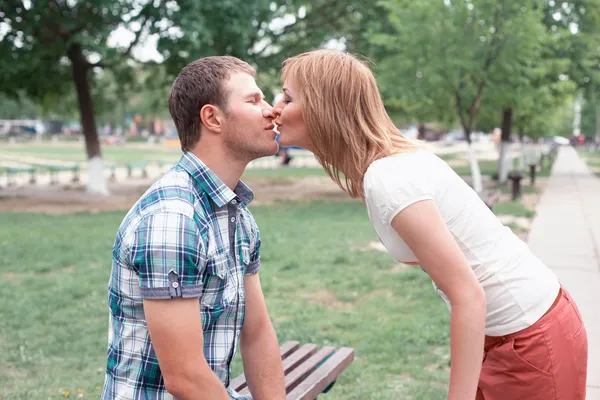 Young couple kissing on bench — Stock Photo, Image