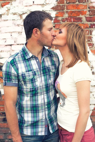 Pareja besándose en ladrillo fondo de la pared —  Fotos de Stock