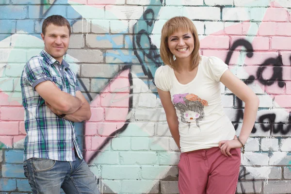 Νεαρό ζευγάρι ενάντια σε τοίχο γκράφιτι — Φωτογραφία Αρχείου