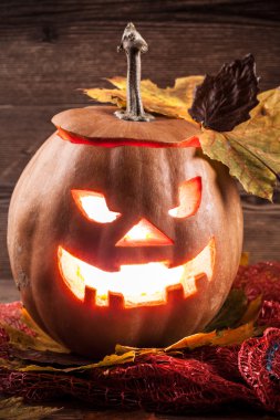 Jack-o-lantern ahşap zemin üzerinde yaprakları ile