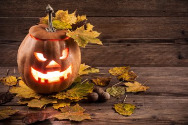 Jack-o-lantern ahşap zemin üzerinde yaprakları ile