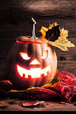 Jack-o-lantern ahşap zemin üzerinde yaprakları ile