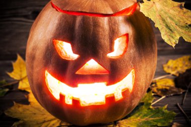 Jack-o-lantern ahşap zemin üzerinde yaprakları ile