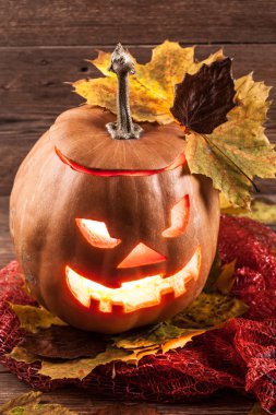 Jack-o-lantern ahşap zemin üzerinde yaprakları ile
