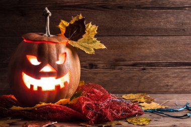 Jack-o-lantern ahşap zemin üzerinde yaprakları ile