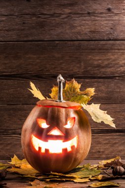 Jack-o-lantern ahşap zemin üzerinde yaprakları ile