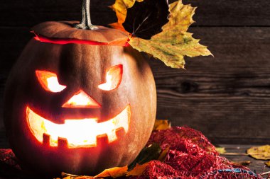 Jack-o-lantern ahşap zemin üzerinde yaprakları ile