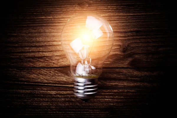 Glowing bulb on the brown wooden background — Stock Photo, Image