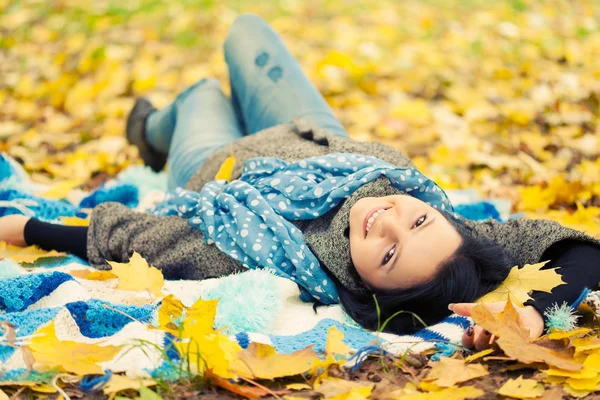 Mulher jovem que põe em folhas de outono — Fotografia de Stock