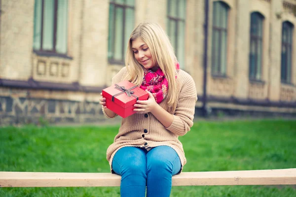 Junge Frau mit Geschenk auf Bank — Stockfoto